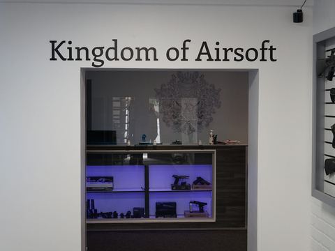 Kingdom of Airsoft showroom with lit display shelves and rifles on the wall