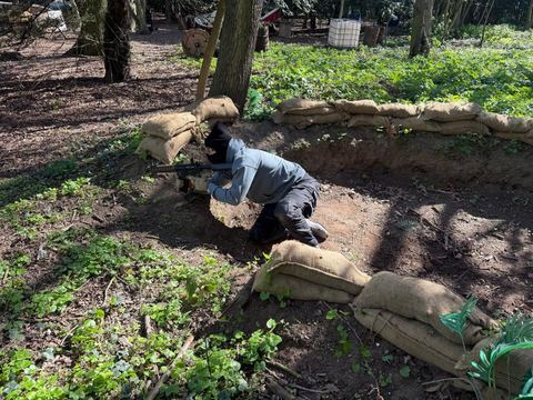 Player in a sandbagged trench in the woodland